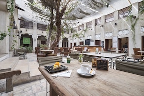 A courtyard with wooden tables and benches, a tree, and a sign for 'XVA Gallery art hotel & cafe Dubai'. - XVA Art Hotel (Dubai)