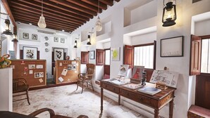 Um quarto amplo com teto de madeira, uma escrivaninha com materiais de arte e quadros nas paredes.