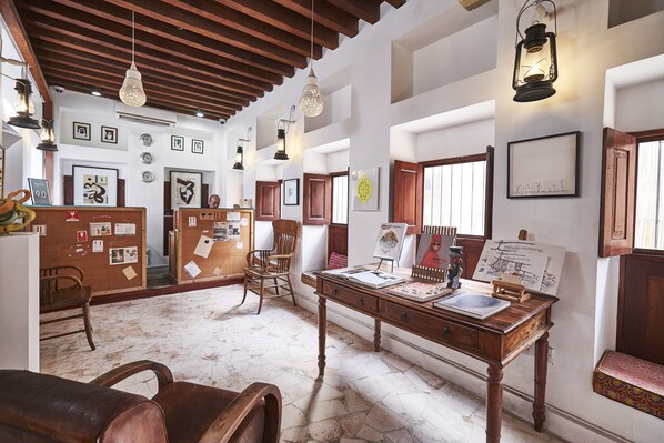 A spacious room with a wooden ceiling, a desk with art supplies, and framed pictures on the walls. - XVA Art Hotel (Dubai)