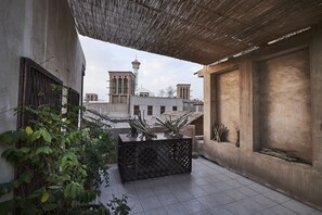 A courtyard with a tiled floor, a wooden pergola, and a view of a mosque with a minaret in the background. - XVA Art Hotel (Dubai)