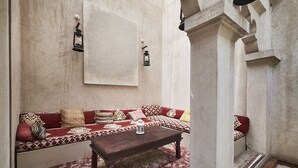 Uma área de estar acolhedora com um sofá e uma mesa de madeira, em frente a uma parede texturizada com um lustre.
