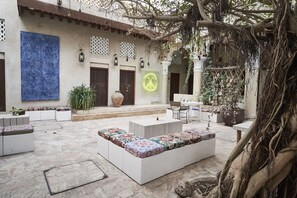 An outdoor seating area with white sofas and a large planter. - XVA Art Hotel (Dubai)