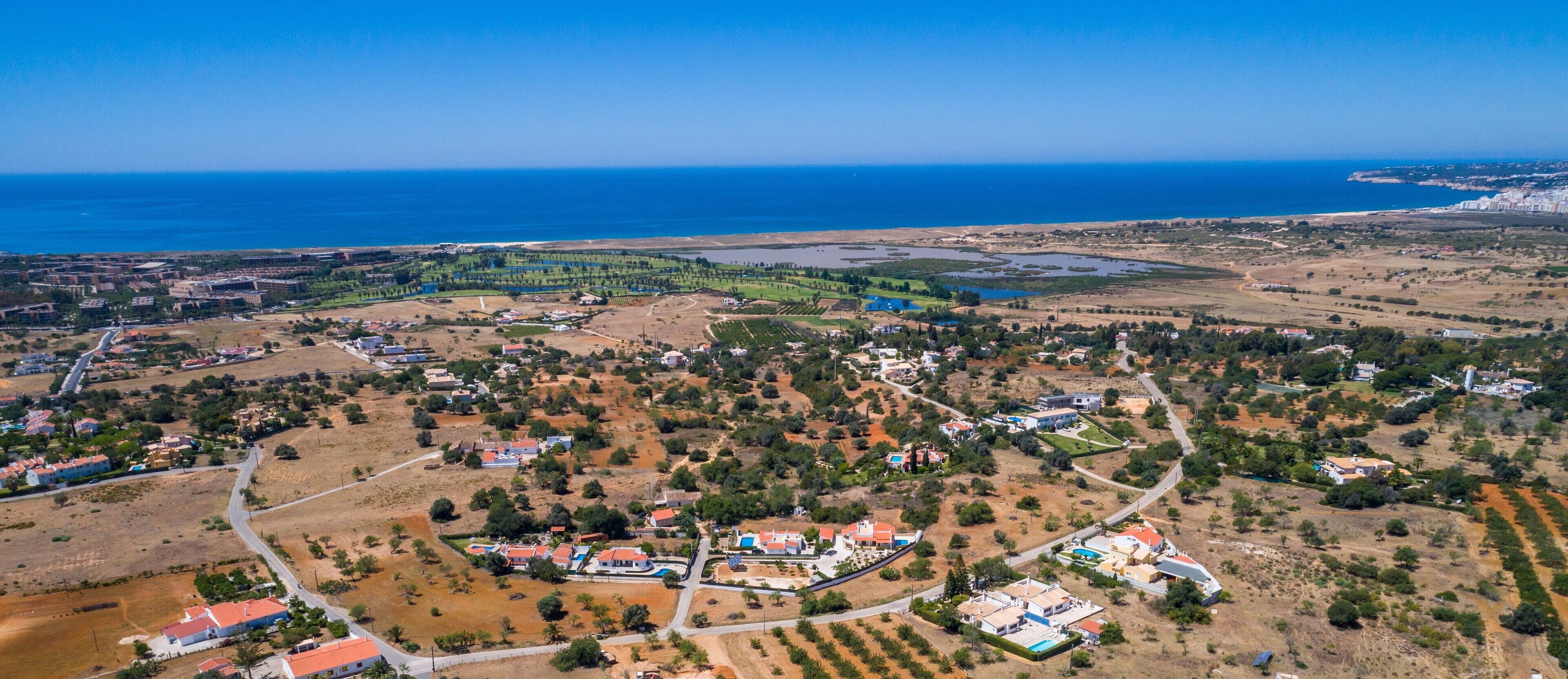 An aerial view of a coastal town with residential areas, a marina, and a large body of water.