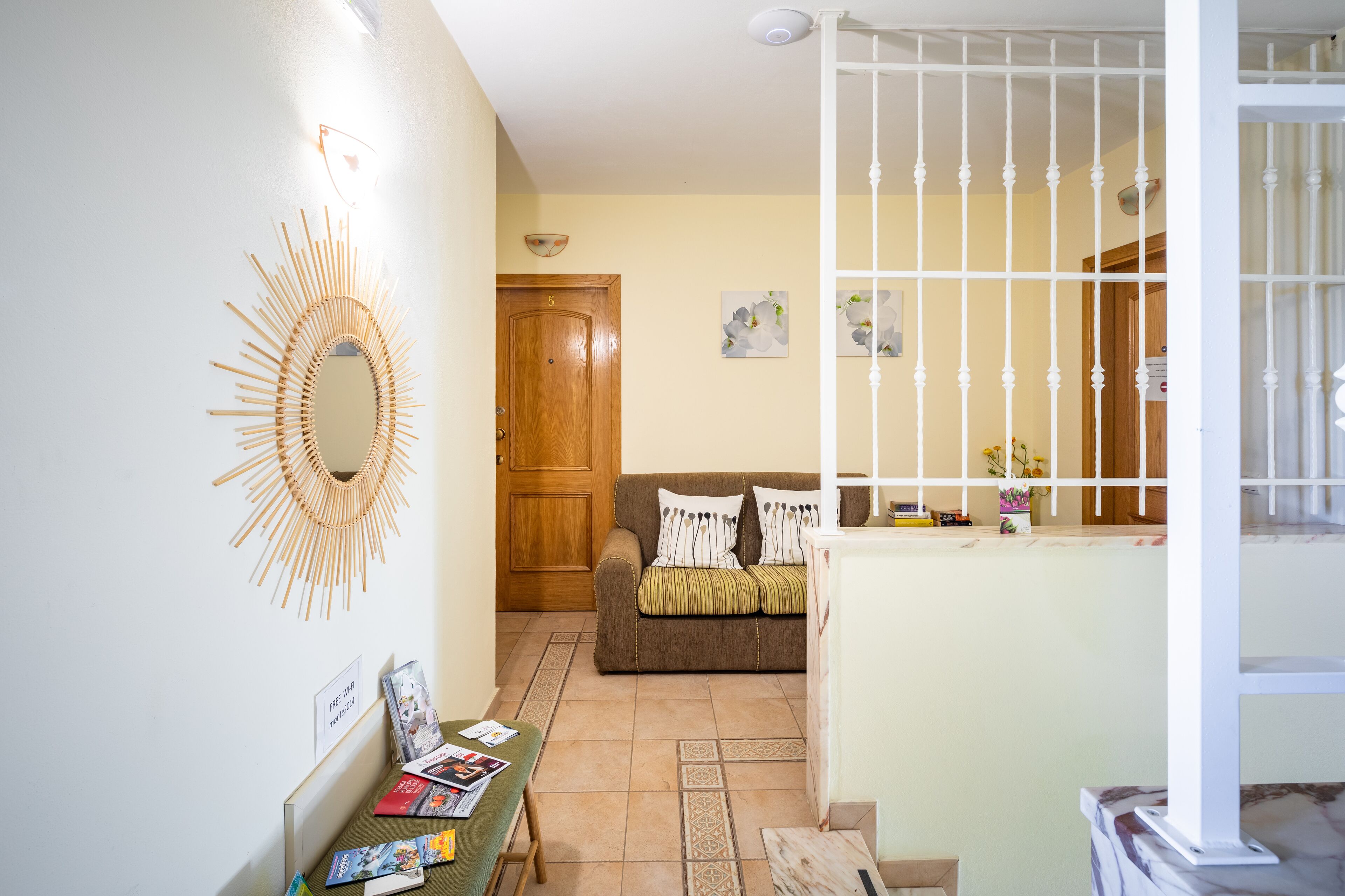 Un salon avec une porte en bois, un canapé, une table basse avec des magazines et un miroir décoratif.