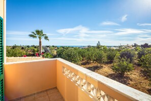 Ein Balkon mit Blick auf eine Küstenlandschaft, Bäume und eine Palme.