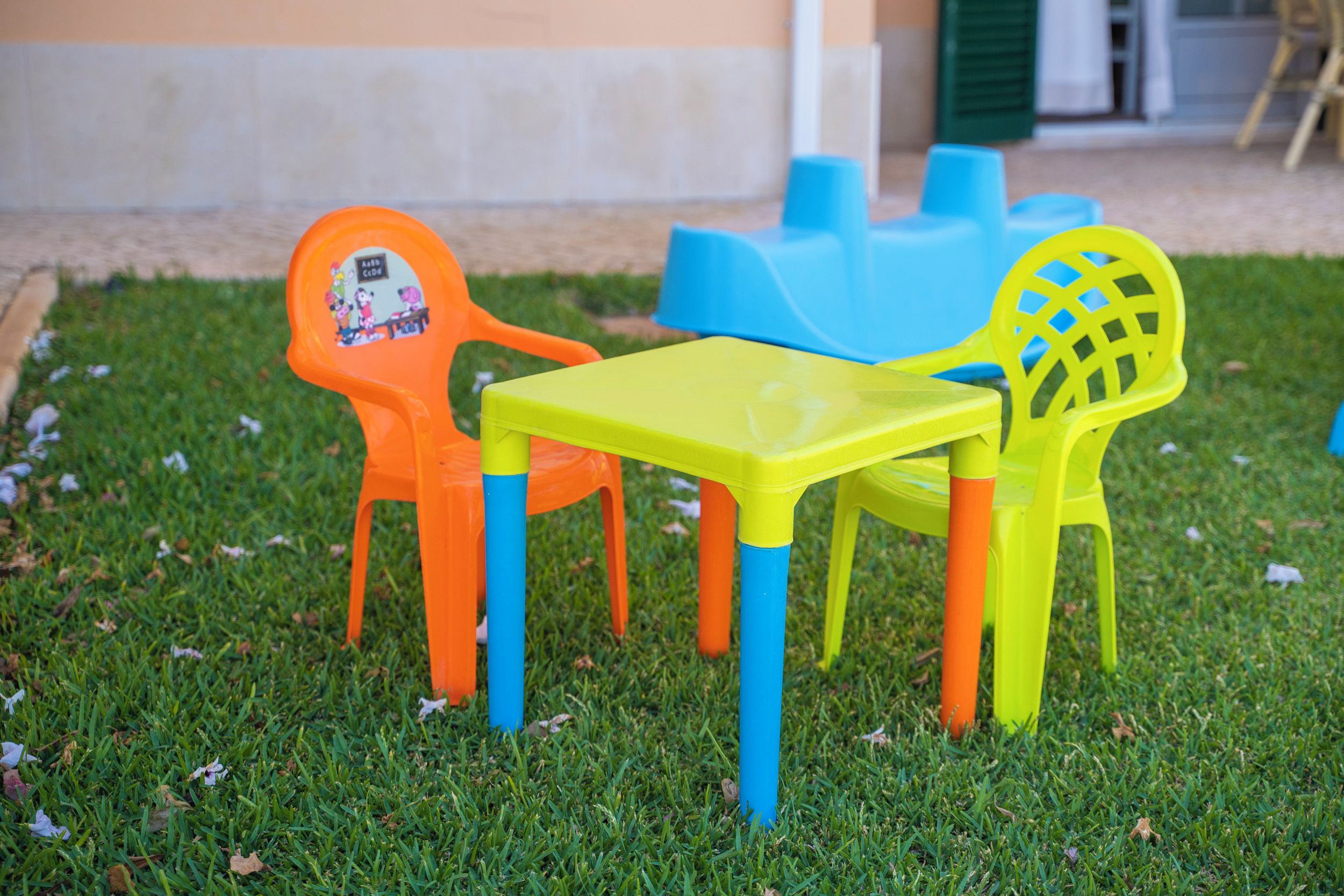 Outdoor plastic chairs and a table on a grassy area.