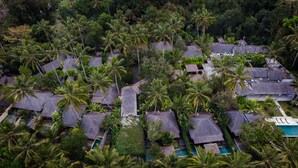 An aerial view of a resort with thatched-roof cottages surrounded by dense palm trees and a swimming pool. - Samkhya Villas (Ubud)