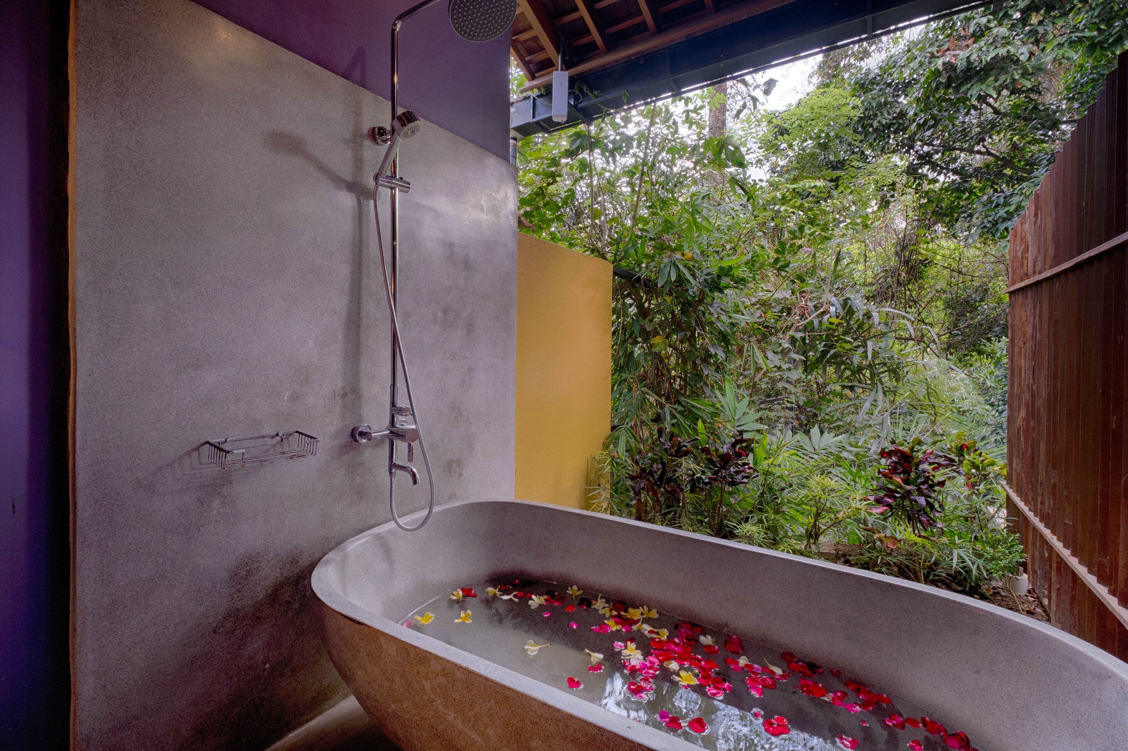 Una vasca da bagno con una doccetta, circondata dal verde.