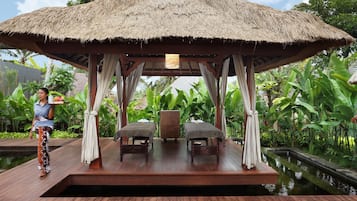Relax in a serene gazebo surrounded by lush greenery and a small water feature.