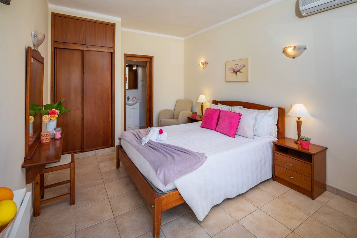 A bedroom with a bed, bedside tables, a desk, a chair, and a wardrobe.