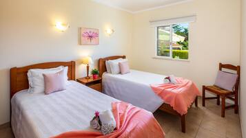 A hotel room with two beds, a window with a view of the garden, and a chair.