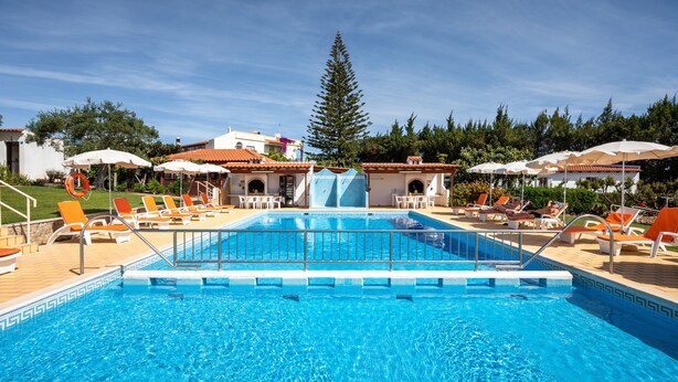 A swimming pool with a water slide, surrounded by lounge chairs and umbrellas. - Flôr da Laranja, Albufeira (Albufeira)