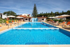 A swimming pool with a water slide, surrounded by lounge chairs and umbrellas. - Flôr da Laranja, Albufeira (Albufeira)