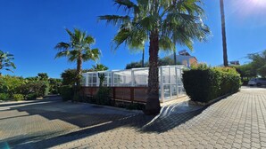 A greenhouse structure with a lattice fence, surrounded by palm trees and a paved walkway. - Flôr da Laranja, Albufeira (Albufeira)