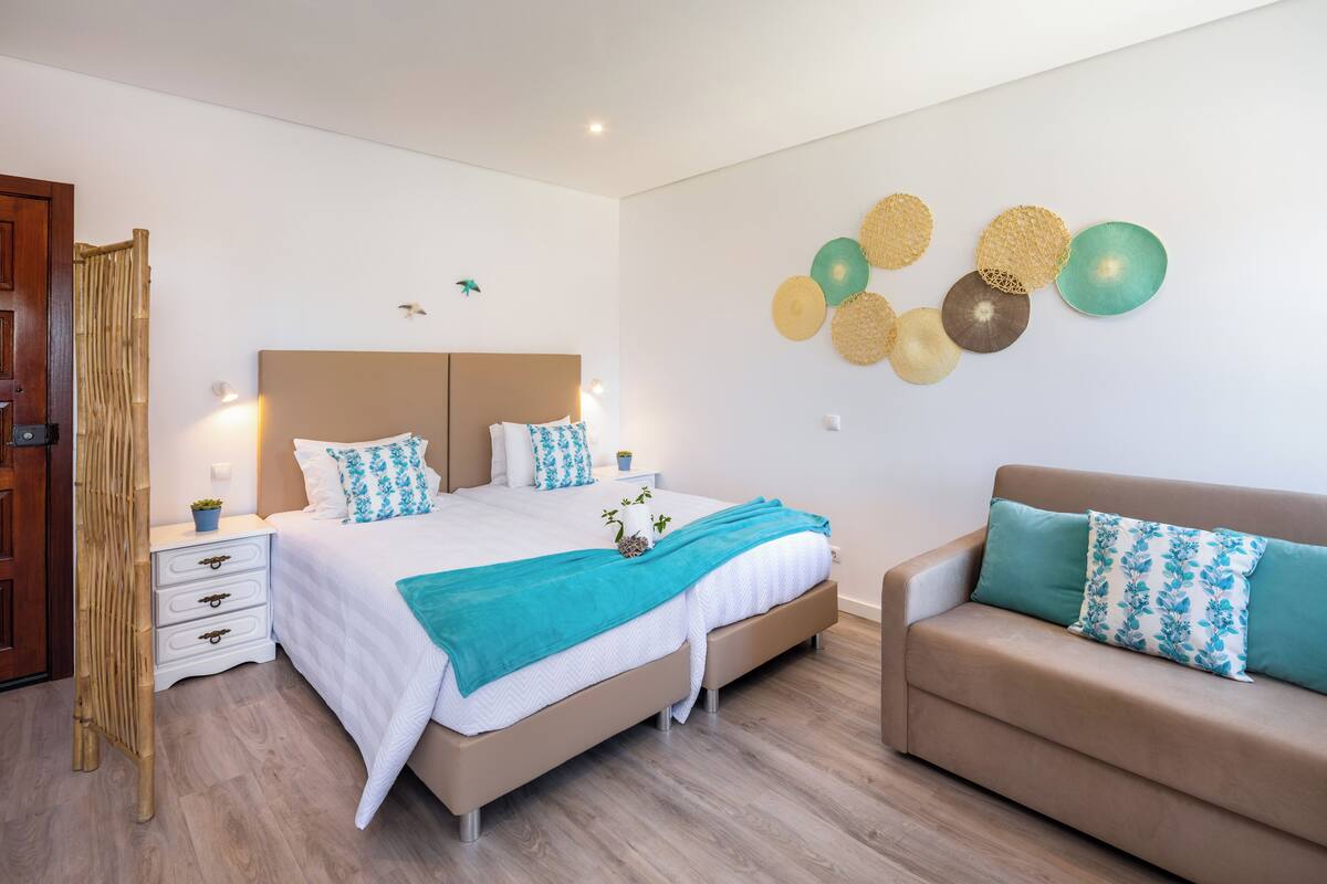 A bedroom with a bed, bedside tables, a sofa, and decorative wall art.