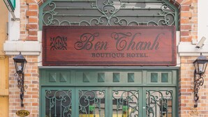 Schild für das Ben Thanh Boutique Hotel mit einer grünen Tür und schmiedeeisernem Zierdekor.