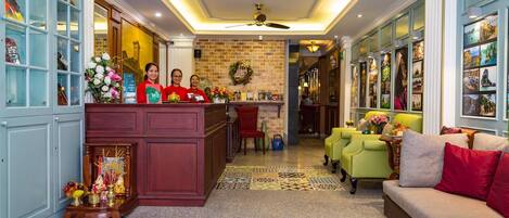 A hotel lobby with a reception desk, a coffee bar, a sofa, and a patterned rug.