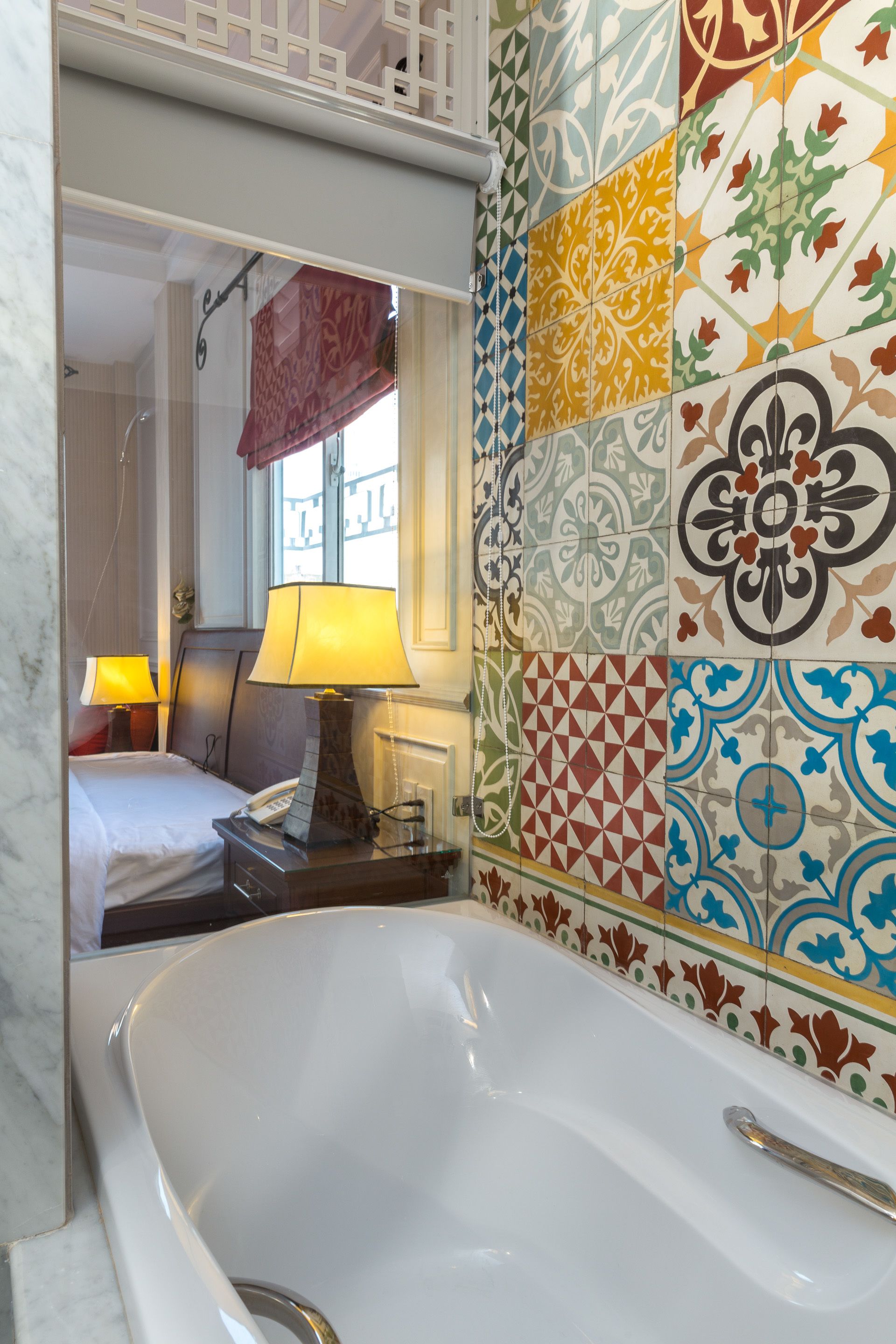 A bathroom with a bathtub, a bed, and a window with a view of buildings.