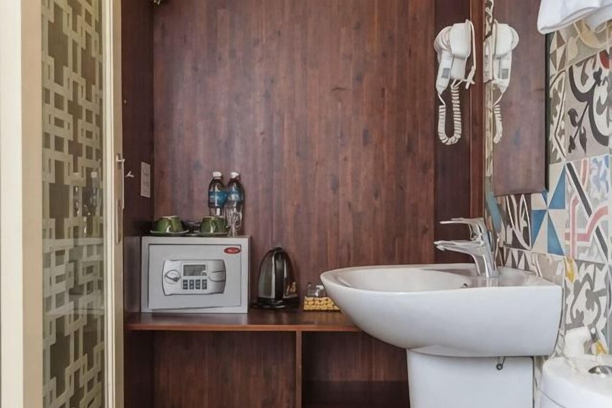 A compact bathroom with a microwave, kettle, and sink.