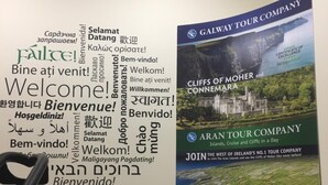Una pared con un mensaje de bienvenida en varios idiomas y un cartel que anuncia a Galway Tour Company.