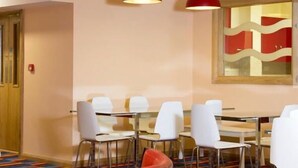 Un salón de conferencias con sillas blancas, una mesa de vidrio y lámparas colgantes rojas.