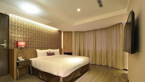 A hotel room with a large bed, a bedside table with a lamp, a TV mounted on the wall, and a patterned wallpaper. - Shin Shin Hotels - Songshan (Taipei)