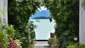 A pathway leading to a body of water with a boat in the distance, surrounded by lush greenery. - Villa Labaron (Koh Samui)