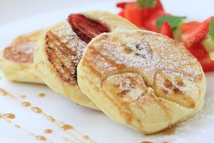 Un plato de tortitas con almíbar y azúcar glas, acompañado de fresas.