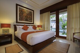 Una cama grande con ropa de cama blanca y marrón, dos mesitas de noche con lámparas, un cuadro en la pared y vistas a zonas verdes por la ventana.
