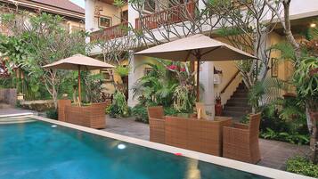 Zona de piscina con mobiliario exterior y una escalera que lleva a un balcón.