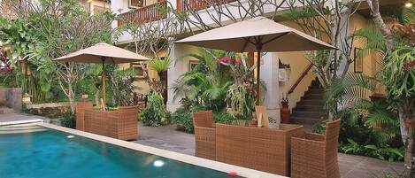 Zona de piscina con mobiliario exterior y una escalera que lleva a un balcón.