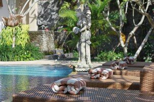 Zona de piscina con sillas de descanso y una estatua.