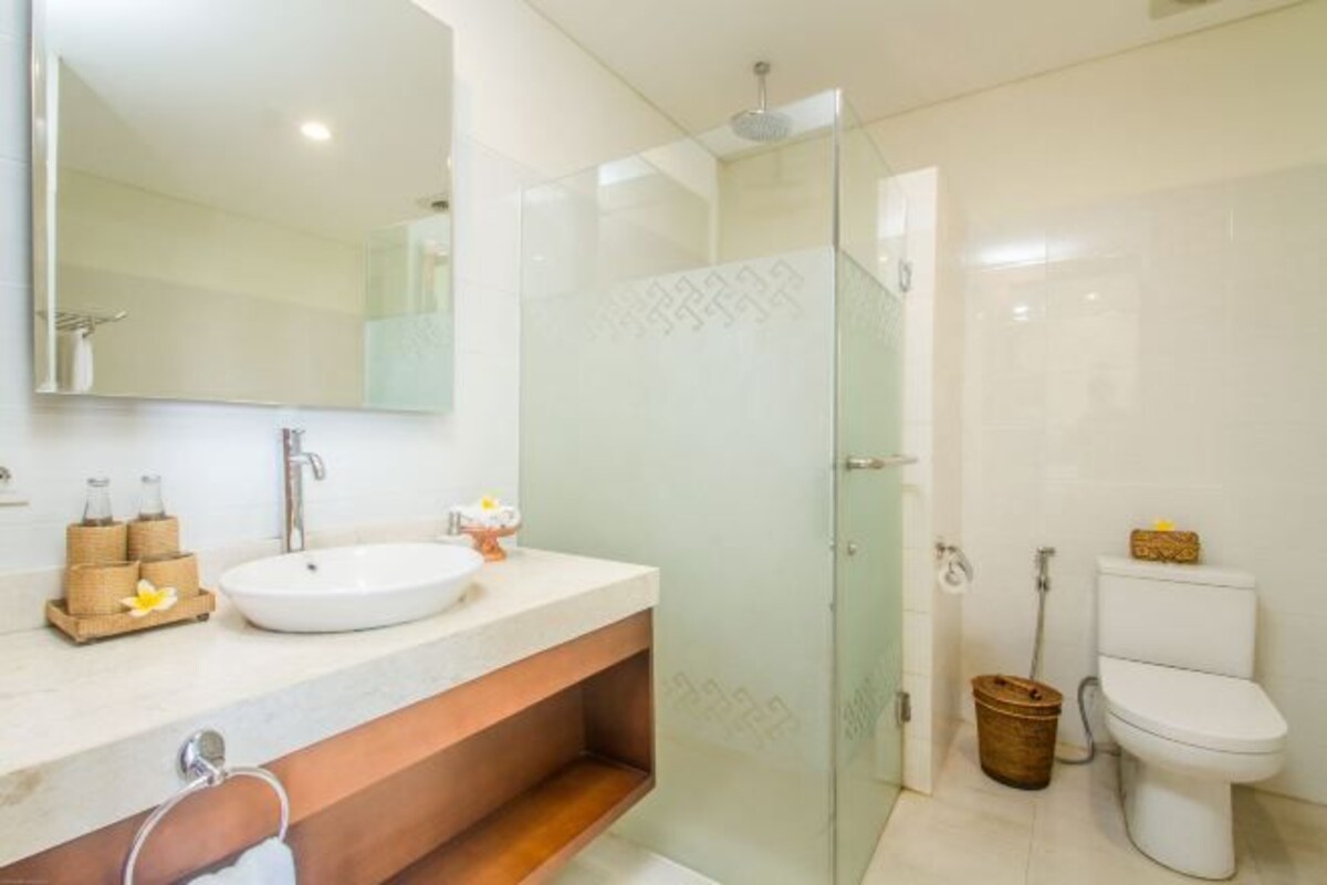 A modern bathroom with a glass-enclosed shower, a white sink, and a toilet.