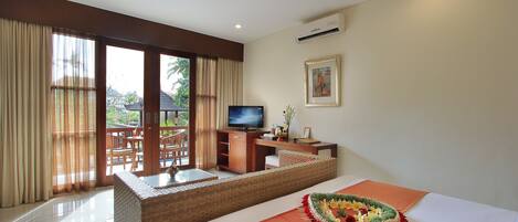 Habitación de hotel con cama, televisor, escritorio y balcón con vista a palmeras.