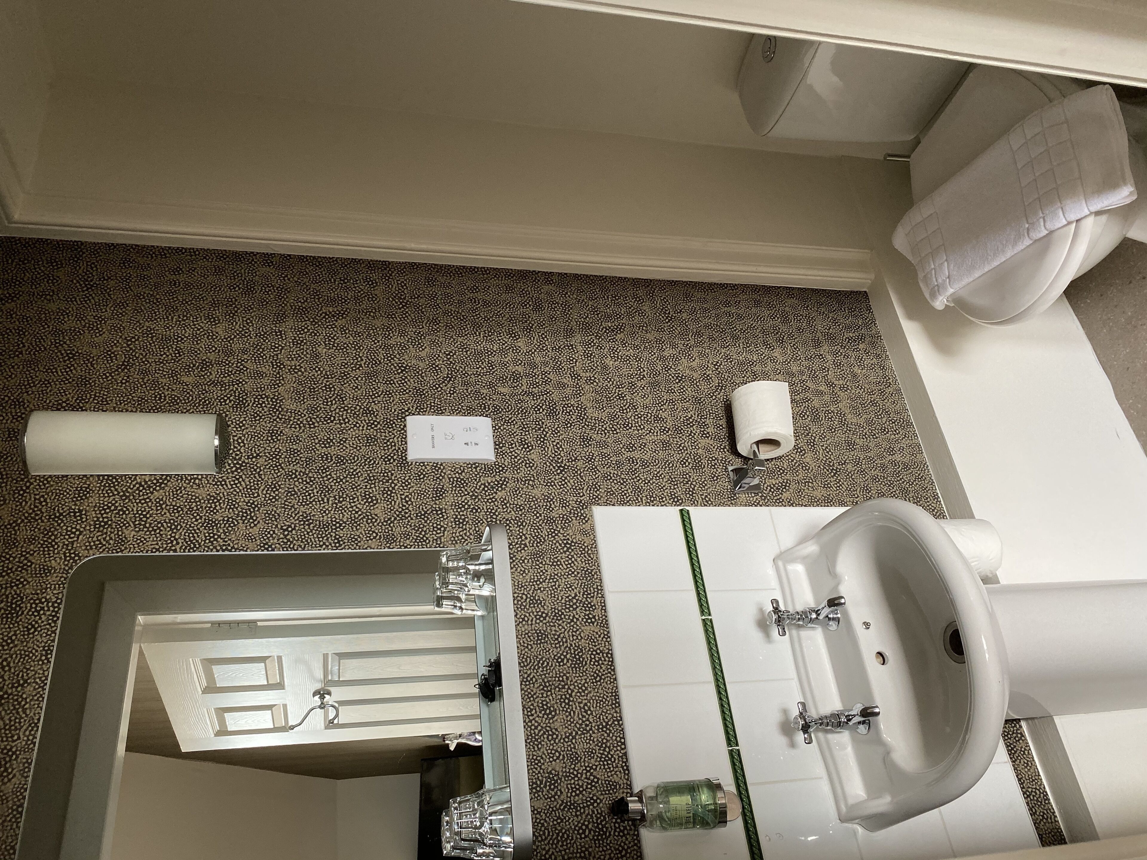 A bathroom with a sink, mirror, toilet, and a towel rack.