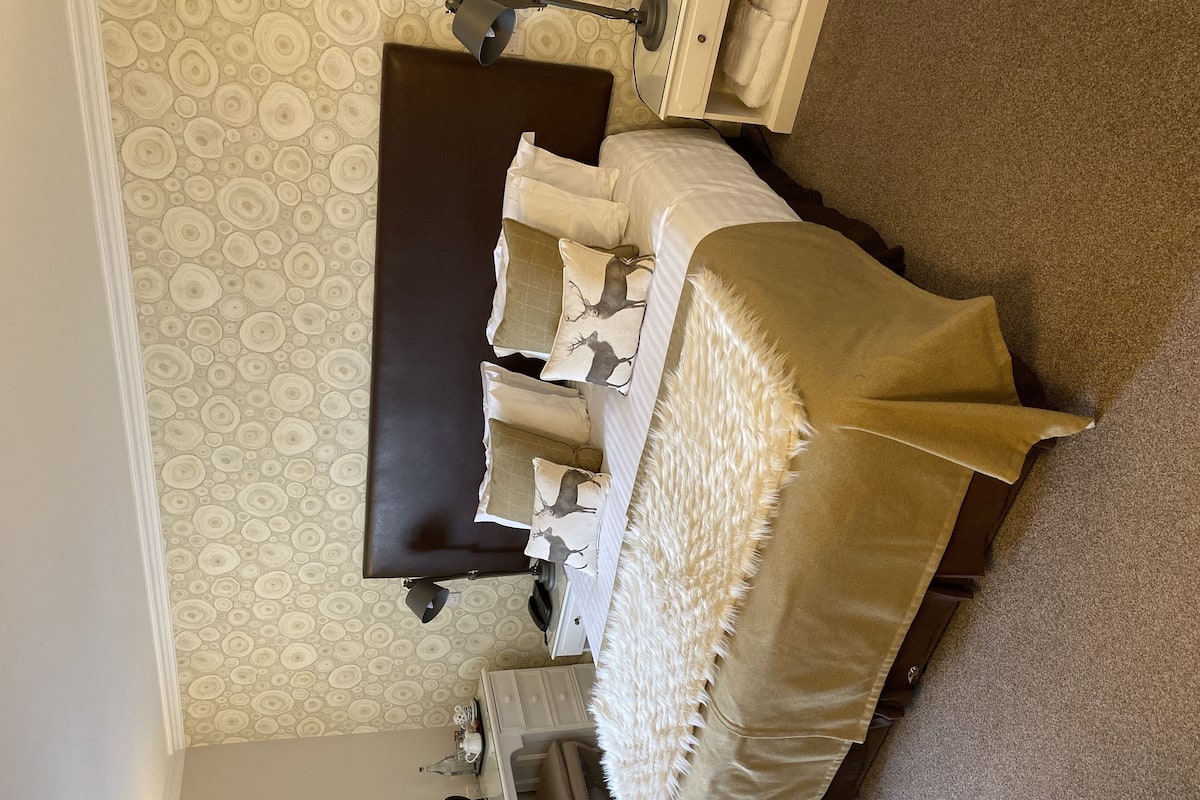 A bedroom with a bed, a dresser, a nightstand, and a lamp.
