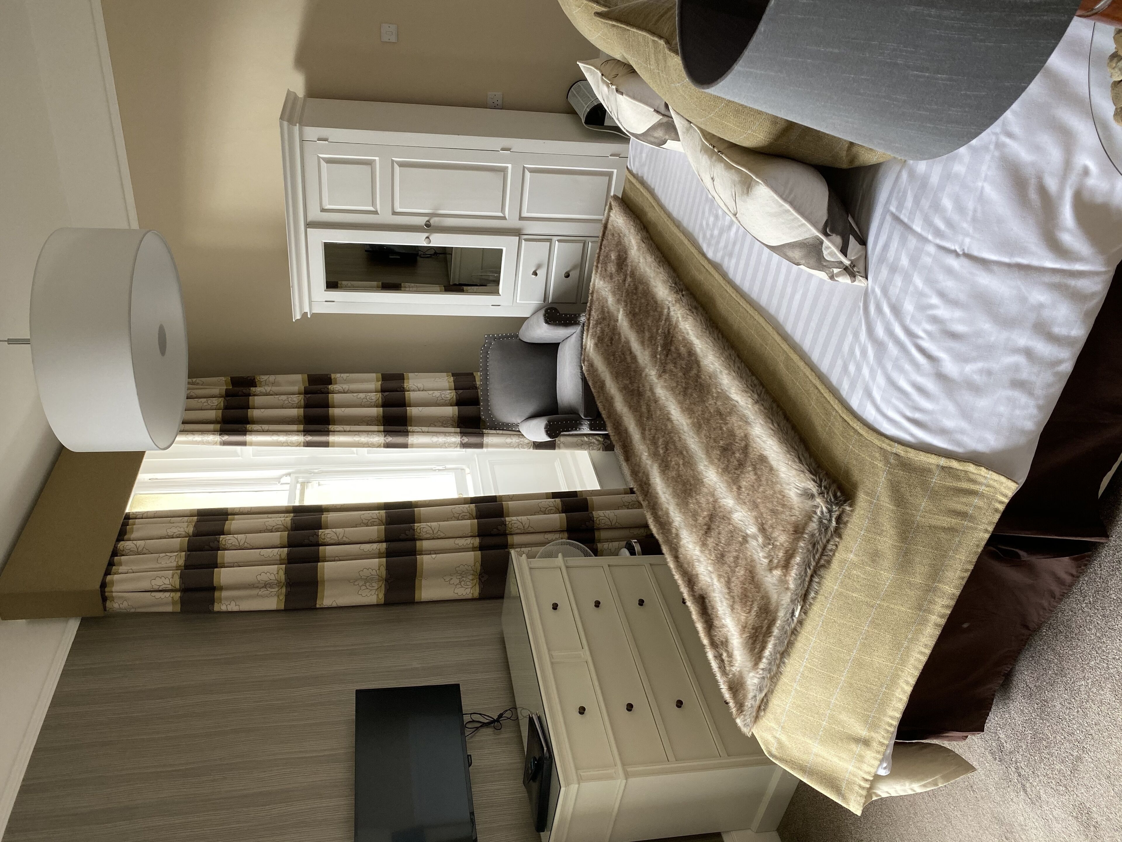 Une chambre à coucher avec un lit, une commode, un bureau et une lampe.