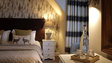 Une chambre d’hôtel avec un lit, une table de chevet, une lampe, une bouteille et des verres sur un plateau.