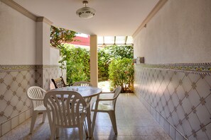 A patio with a tiled floor, white chairs, and a table.