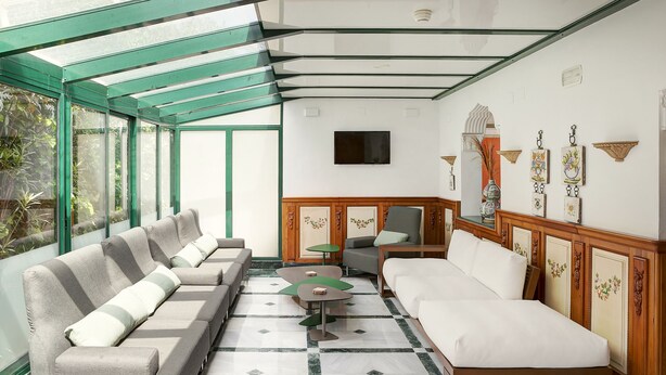 A modern hotel room with a glass ceiling, a sofa set, a bed, a TV, and decorative wall art. - Hotel Rosa (Denia)