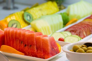 A variety of fresh fruits including watermelon, pineapple, and kiwi on a white plate.