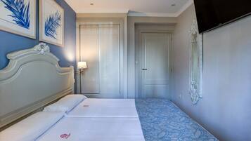 A hotel room with a large bed, a bedside table with a lamp, and a TV mounted on the wall.