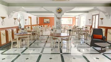 Un comedor amplio con varias mesas y sillas, una pieza decorativa central y una combinación de mobiliario tradicional y moderno.
