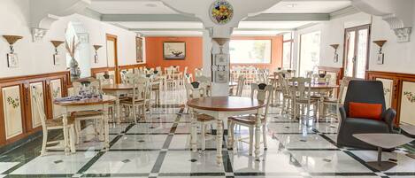 A spacious dining area with multiple tables and chairs, a central decorative piece, and a mix of traditional and modern seating.