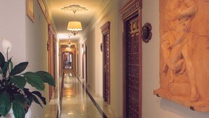 A hallway with a marble floor, wooden doors, and a large wall-mounted sculpture. - Hotel Rosa (Denia)