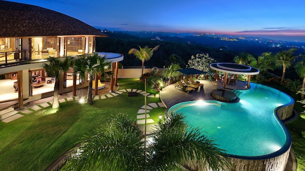 A modern house with a swimming pool, outdoor seating, and a view of the landscape.