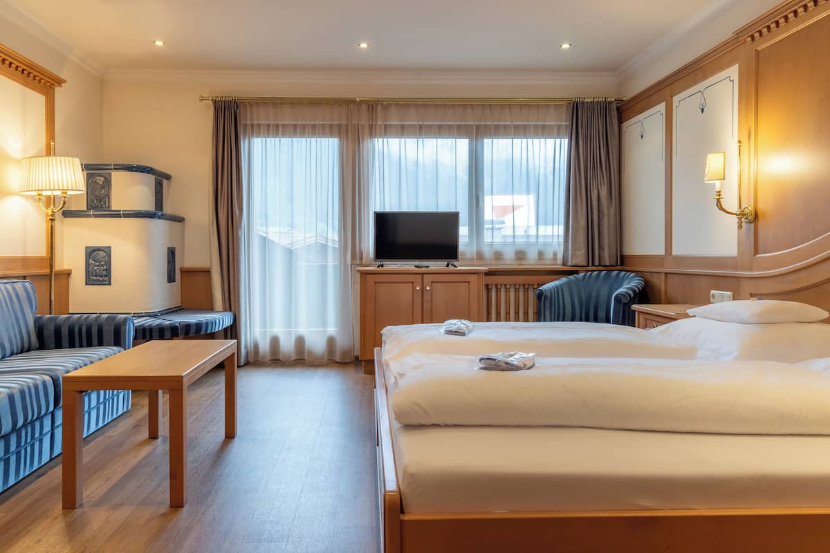 Una habitación de hotel con una cama grande, televisión, sofá y escritorio.