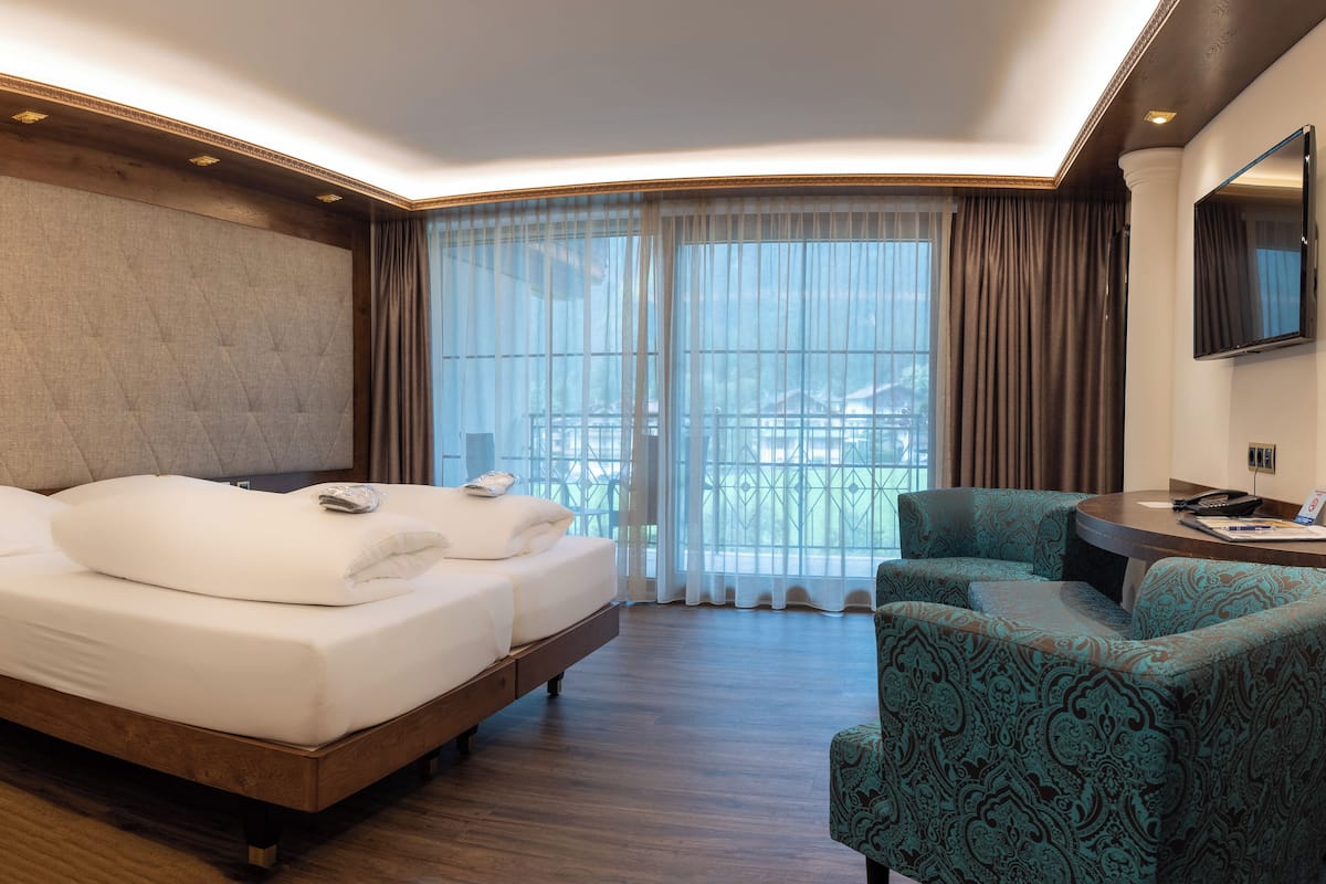 Habitación de hotel con cama, escritorio, silla y televisor.