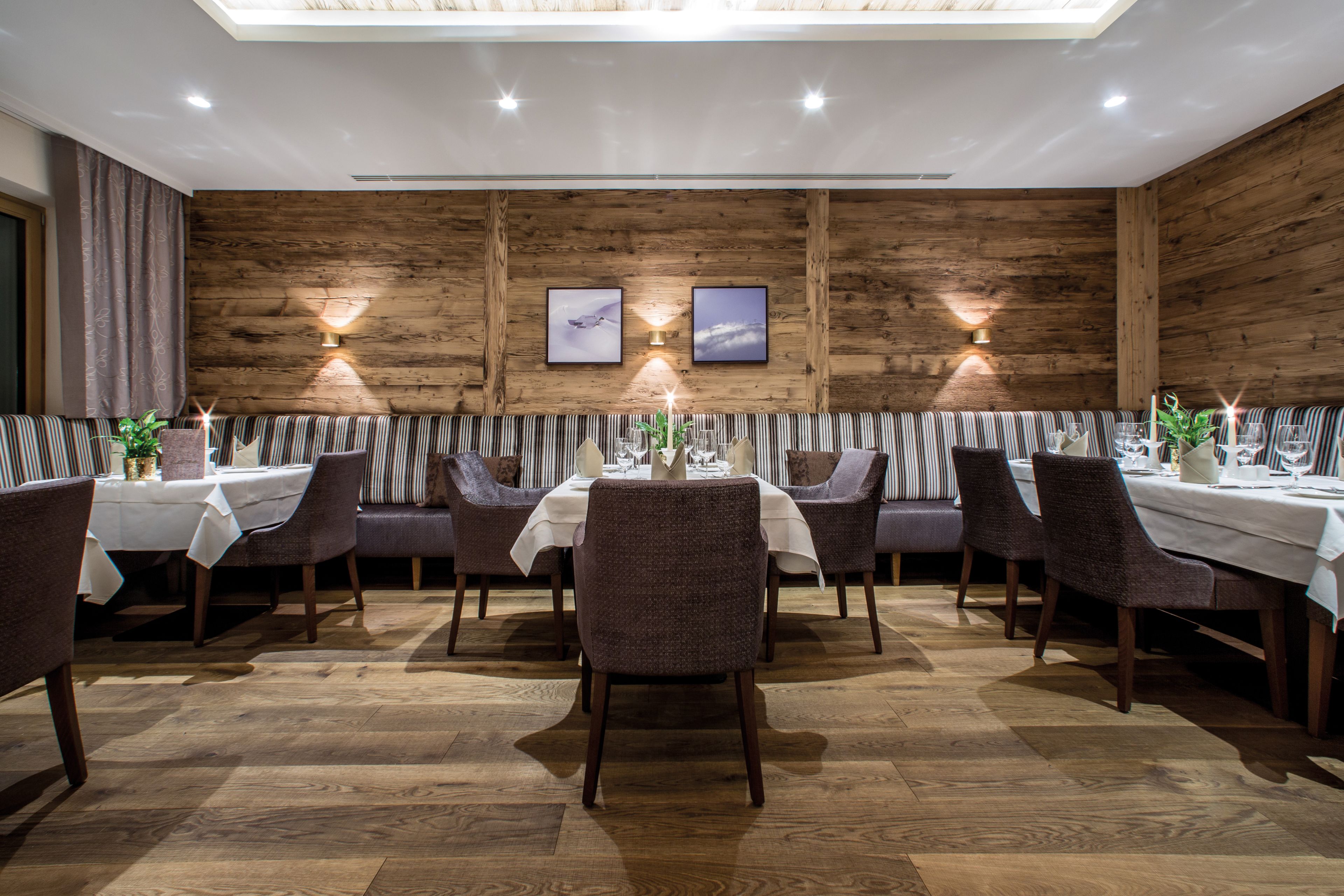 A restaurant with wooden walls, striped booths, and a central dining table with chairs.