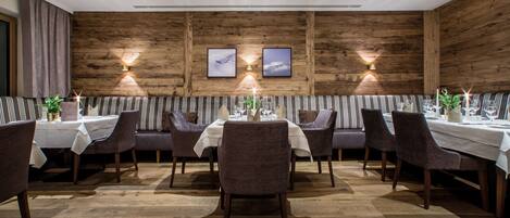 A restaurant with wooden walls, striped booths, and a central dining table with chairs.